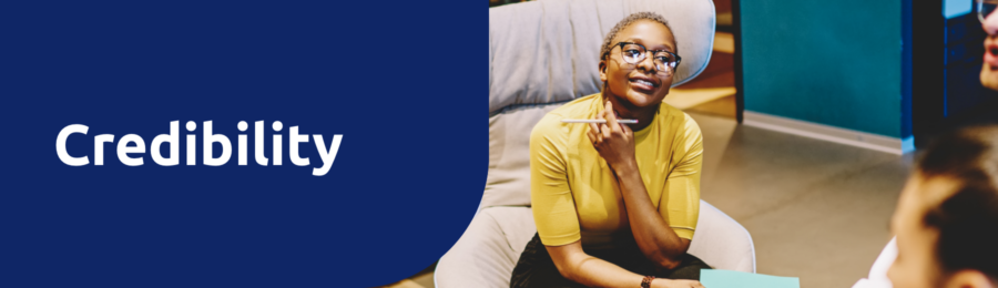 Credibility heading, image behind shows young adult, female with short hair and glasses - speaking to someone facing away from the camera, and concentrating.